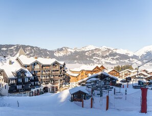 A snow-covered mountain resort with wooden buildings, ski lifts, and a clear view of snow-capped mountains. - Mountain View Stay Near Morillon Ski Slopes (Morillon)