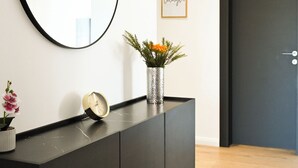 Et moderne værelse med et mørkt konsolbord, et rundt spejl, et billede med ordet 'laugh' og en lille potteplante.