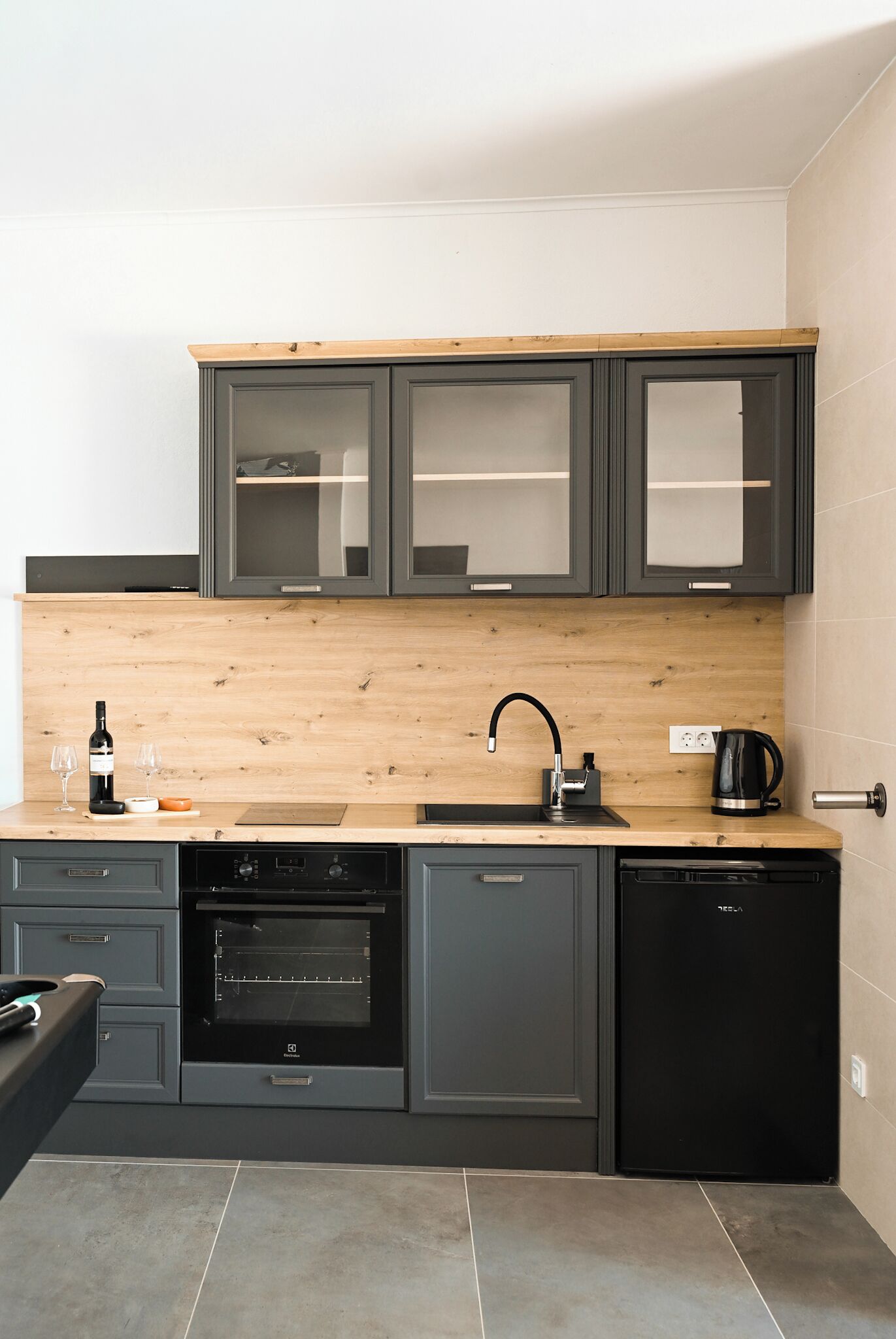 Una cocina moderna con armarios oscuros, encimera de madera, horno empotrado y lavavajillas.