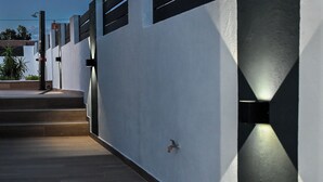Une façade moderne avec un mur en béton, un portail en métal et un escalier menant à un niveau supérieur.
