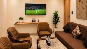 Una sala de estar con televisor, sofás, sillones, una mesa de centro y un ventilador de techo.