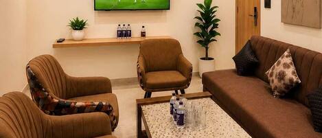 A living room with a TV, sofas, chairs, a coffee table, and a ceiling fan.