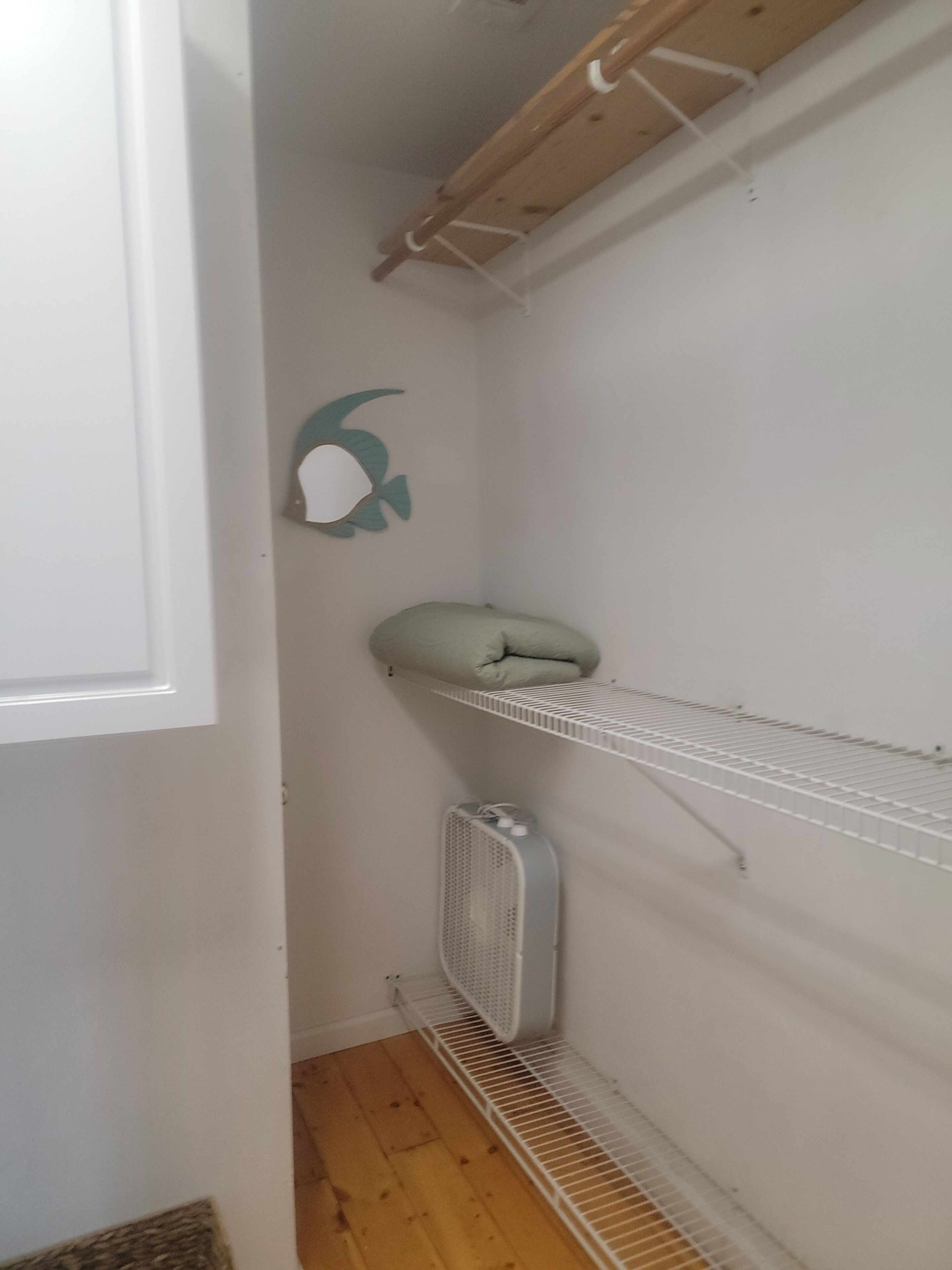 Un coin de pièce avec une porte blanche, un radiateur blanc et une étagère blanche.
