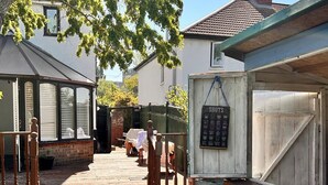 A wooden deck leading to a house with a covered porch and a small shed with a sign. - Baoyan Greenwich spacious 3 bedrooms house (London)
