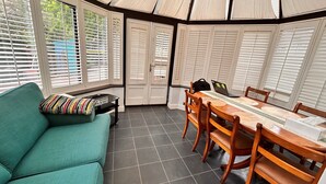 A conservatory with a dining table, chairs, a sofa, and a laptop on the table. - Baoyan Greenwich spacious 3 bedrooms house (London)