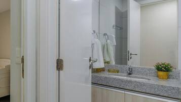 Un baño con lavamanos doble, espejo, planta en maceta y toallero.