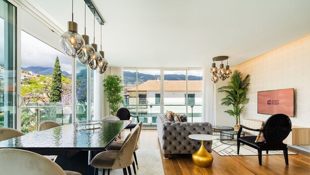 Un salon moderne avec un coin repas, de grandes fenêtres et une vue sur la ville.