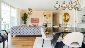 Un salon moderne avec un canapé capitonné, une table à manger avec des chaises, un téléviseur et un mur décoratif.