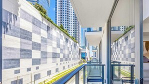 A modern building with a checkered facade, a glass balcony with a metal railing, and a view of high-rise buildings. - Luxe 1-BR at Miami Worldcenter | Skyline (Miami)