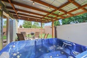 Ein Whirlpool unter einer überdachten Terrasse mit Holzbalkendecke und Stühlen.