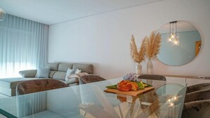 Uma sala de estar moderna com uma mesa de jantar de vidro, um conjunto de sofá e um espelho redondo na parede.