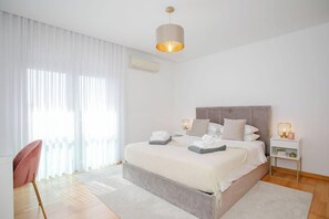 Une chambre à coucher moderne avec un grand lit, une table de chevet, une chaise et un luminaire suspendu.