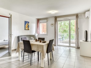A dining area with a table set for four, a sofa, a TV, and a balcony with a view. - Retreat, Balcony, Pool & Gym (Argelès-sur-Mer)