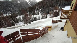 A snow-covered outdoor area with a wooden bench and a yellow building. - Studio Apartment 'Le Refuge Douillet' with Mountain View and Private Terrace (La Plagne Tarentaise)