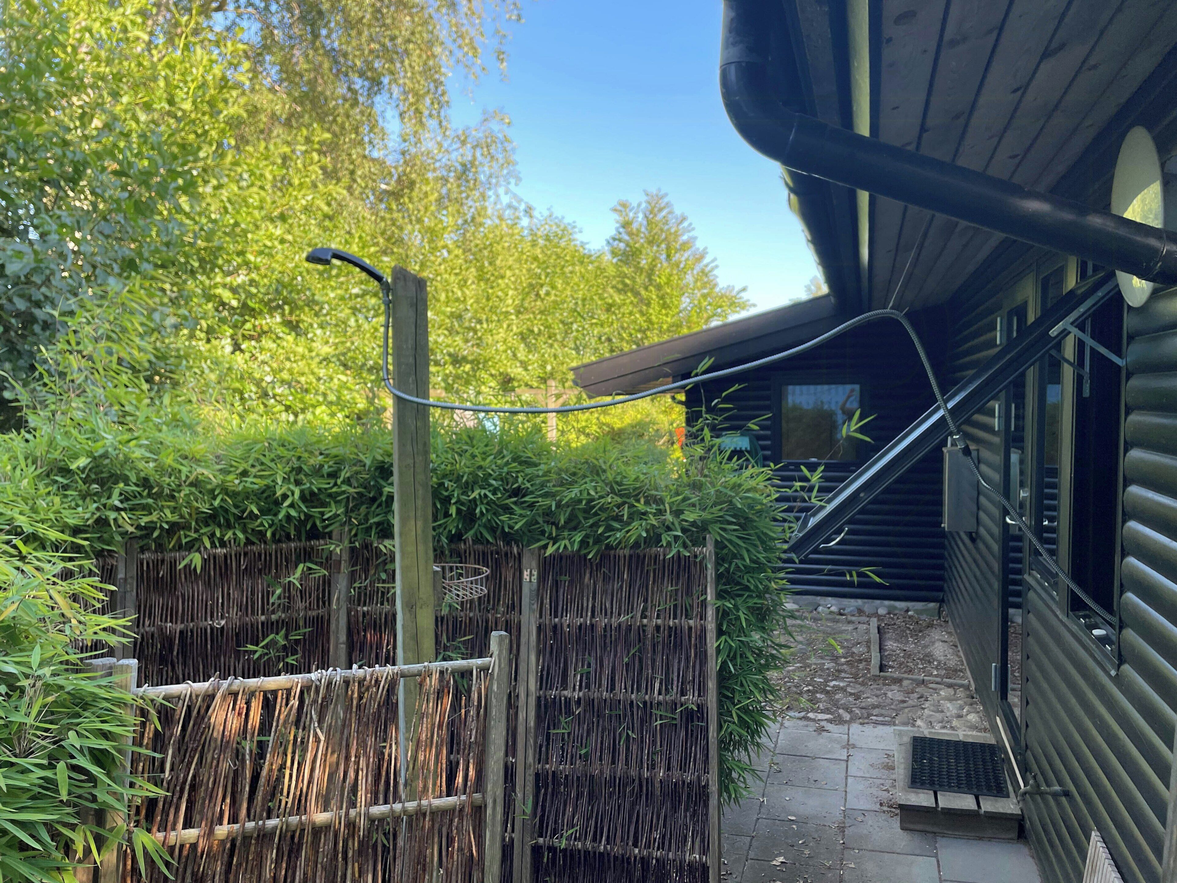 Une clôture en bois, une plante de bambou et un bâtiment avec une fenêtre.