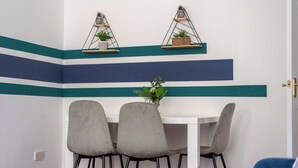 A dining area with a white table, three grey chairs, and two wall-mounted shelves with plants. - Spacious Apt Stay - Near City Centre & Tram -Walk to Leith (Edinburgh)