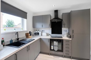 A modern kitchen with a black sink, white appliances, grey cabinets, and a window with a view. - Free Parking -15 Mins to Airport - Nr City Centre (Newcastle)