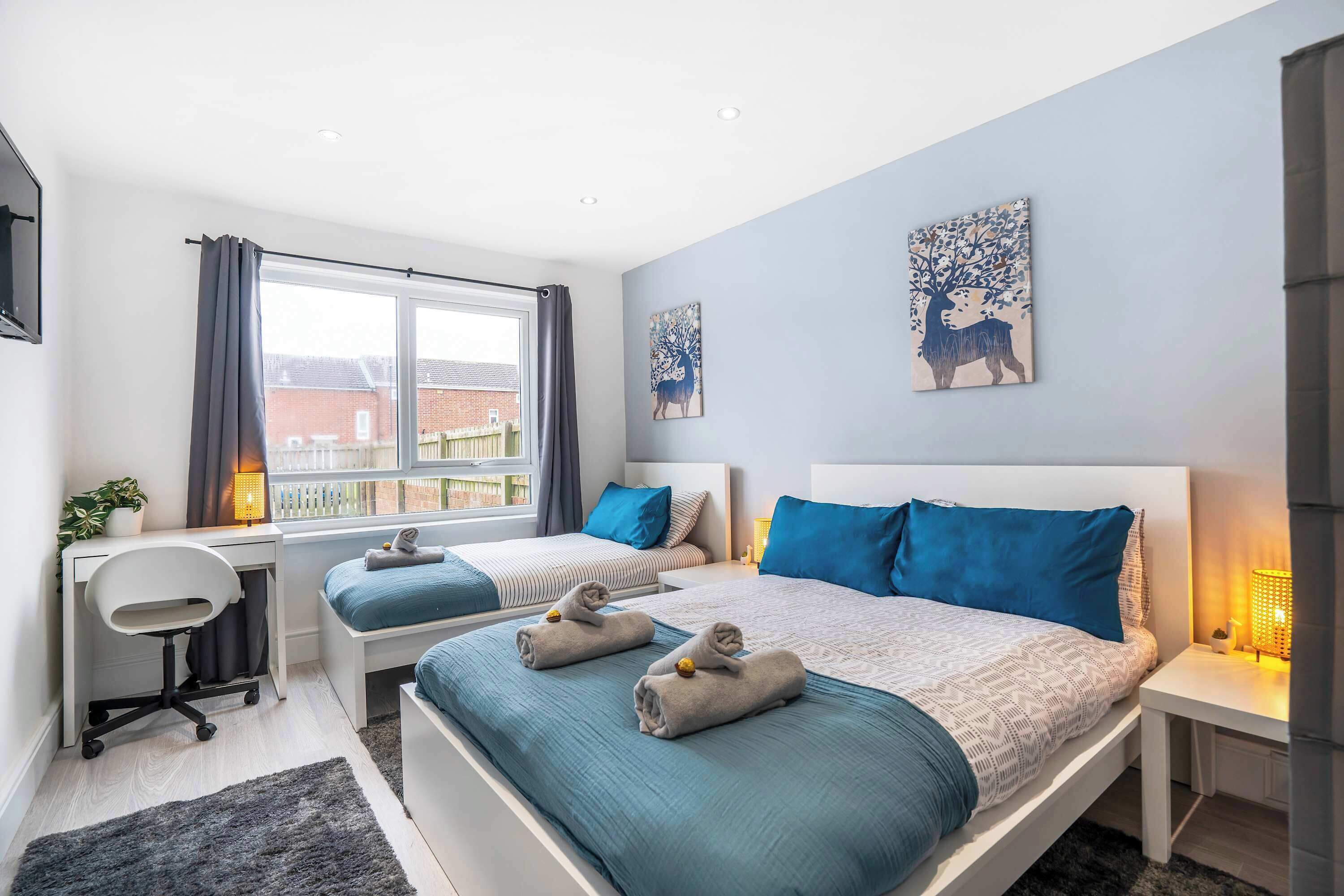 Una camera da letto con due letti, una scrivania, una sedia e un'ampia finestra.