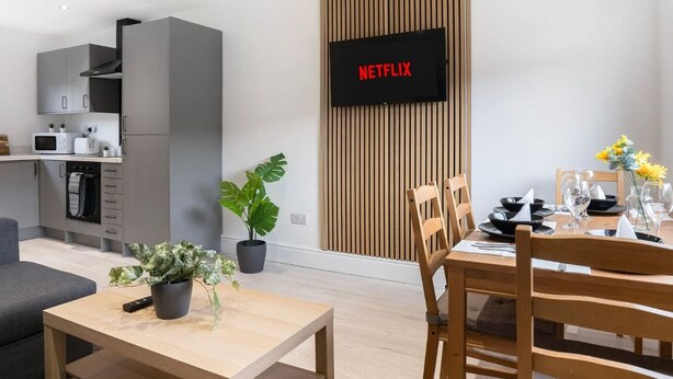 A modern kitchen with grey cabinets, a microwave, and a TV displaying 'NETFLIX'. - Spacious 6-Bed Home for 9, Free Parking, Nr Centre (Newcastle)