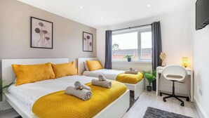 A modern hotel room with two beds, a desk, and a window with curtains. - Spacious 6-Bed Home for 9, Free Parking, Nr Centre (Newcastle)