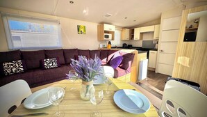 Un espacio habitable compacto con sofá, mesa de comedor y zona de cocina.
