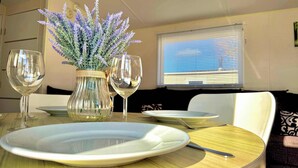 Una mesa de comedor con dos copas de vino, un florero con lavanda y un plato.