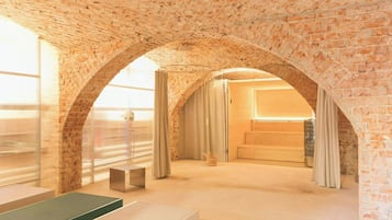 A room with a brick ceiling, a large window, a shower, and a bed.