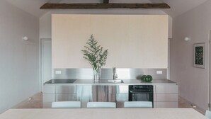 A modern kitchen with stainless steel appliances, a wooden ceiling beam, and a minimalist design. - Renovated commandery on the Elbe with sauna (Werben)