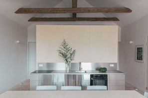 Eine moderne Küche mit Edelstahlgeräten, einem Holzbalken an der Decke und minimalistischem Design.