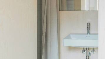 A bathroom with a shower curtain, a sink, and a mirror.