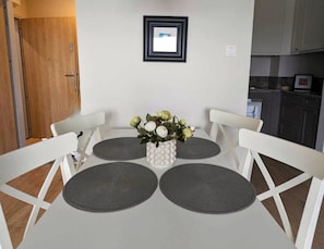 Ein Esstisch mit vier Stühlen, eine Vase mit Blumen und ein gerahmtes Bild an der Wand.