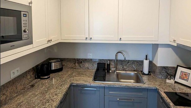 A kitchen with white cabinets, a stainless steel sink, a microwave, a toaster, and a coffee maker. - Apartment 50 m2 for 3 People, Dziwnow (Dziwnów)