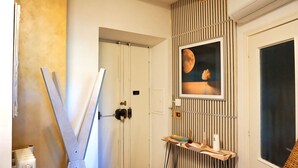 Ein Zimmer mit Tür, Heizkörper, einem Bilderrahmen mit einem Mondmotiv und einem Regal mit Gegenständen.