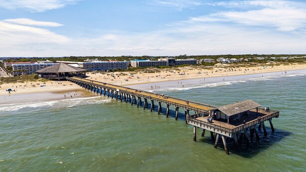 A pier extending into the water with a beach and buildings in the background. - Renovated, Quick Walk to Beach + Restaurants by Tybee Cottages (Tybee Island)