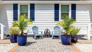 A house with a porch, two chairs, and potted plants. - Renovated, Quick Walk to Beach + Restaurants by Tybee Cottages (Tybee Island)