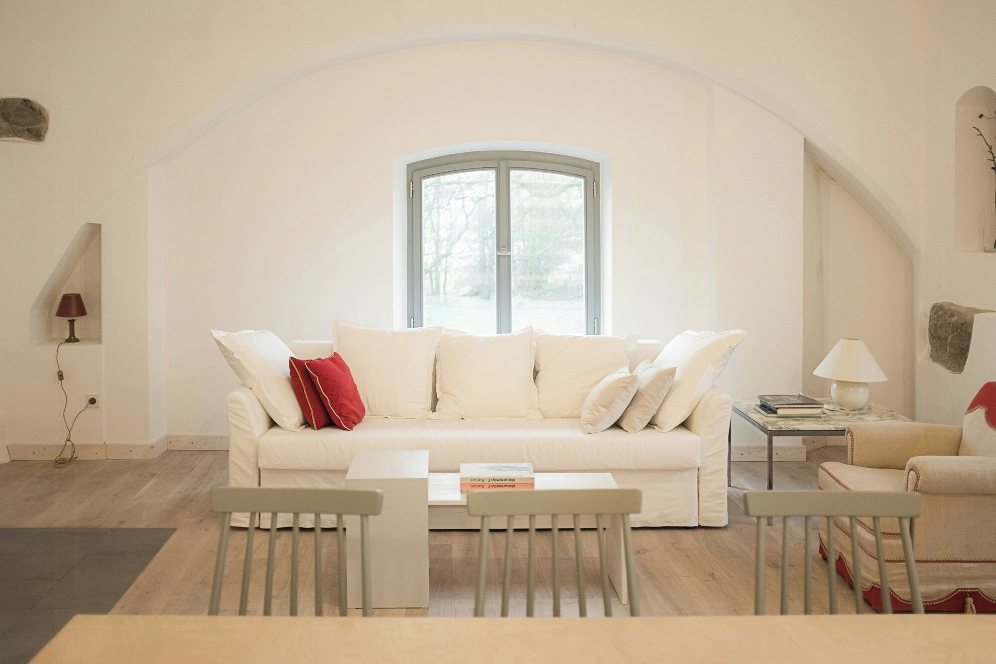 A living room with a white sofa, a small table, a chair, and a lamp.