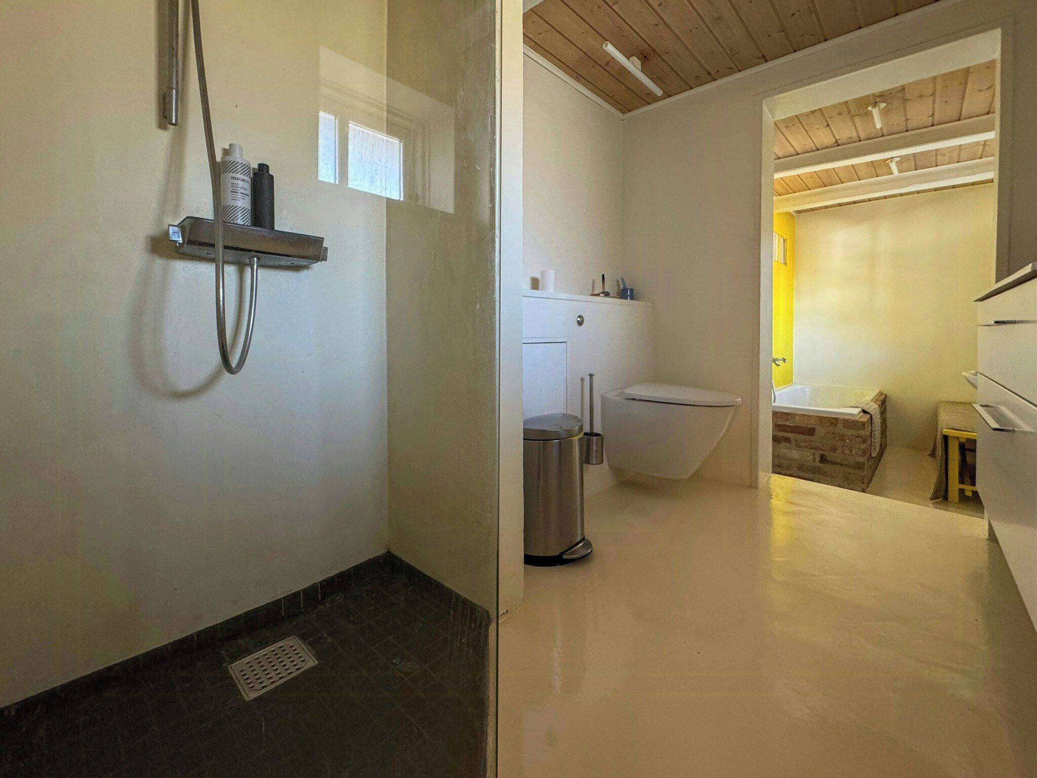 A bathroom with a shower, toilet, and a small sink.
