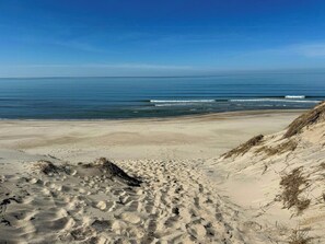 Ein sandiger Strand mit sanften Wellen und blauem Himmel.