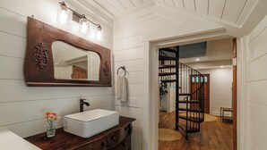 A bathroom with a wooden vanity, a large mirror, and a white sink.