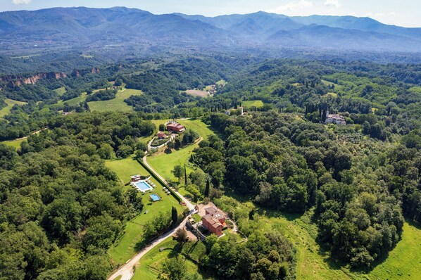 An aerial view of a property with a swimming pool, a red-roofed building, and surrounding lush greenery. - Dog-friendly barn with views in Reggello (Reggello)