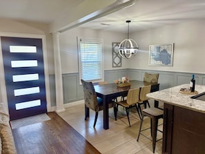 A dining area with a dark wooden table, patterned chairs, a chandelier, and a map on the wall. - Mt Pleasant Retreat Under the Oaks (Mount Pleasant)