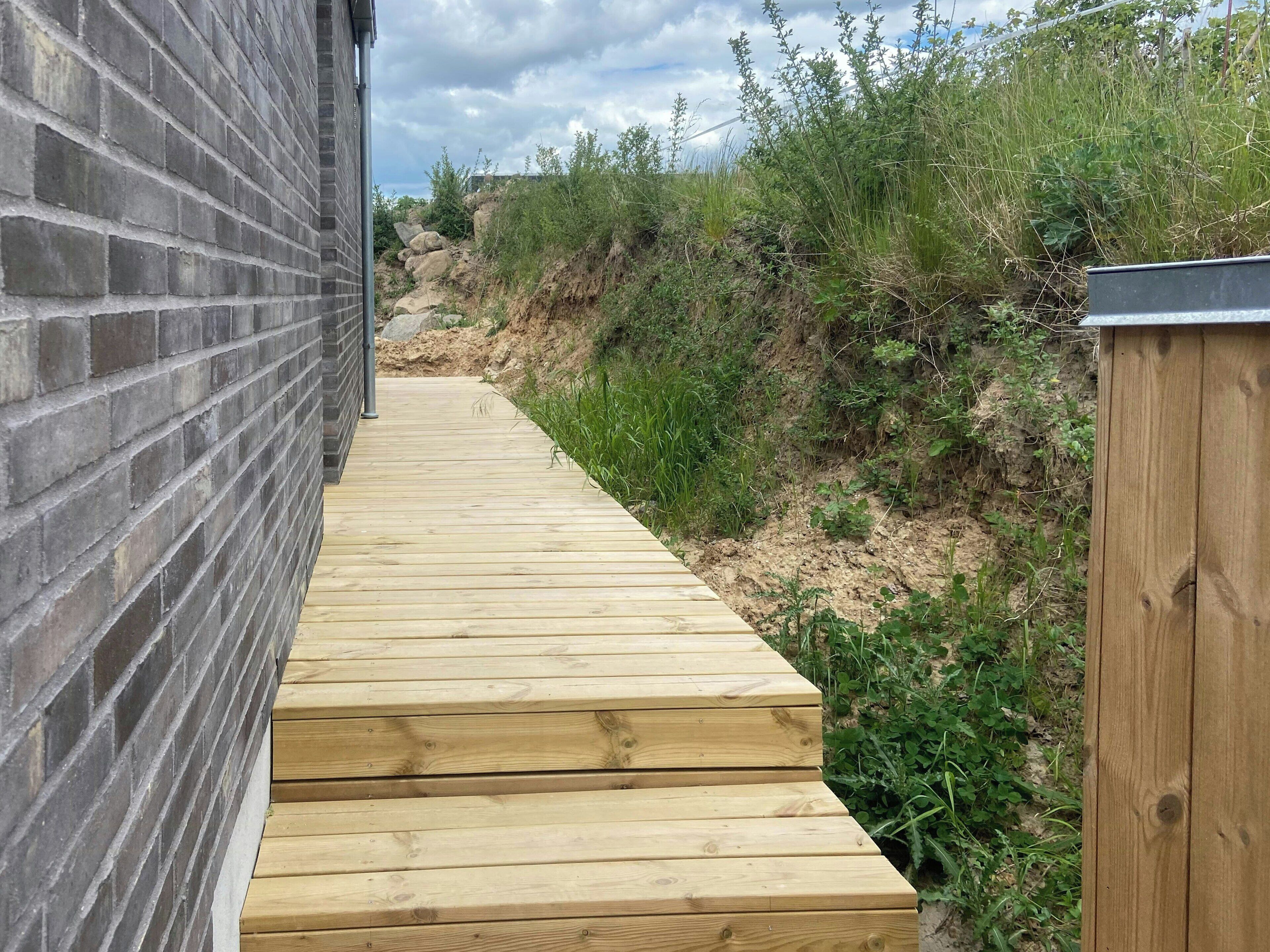 A wooden pathway leading to a brick wall.