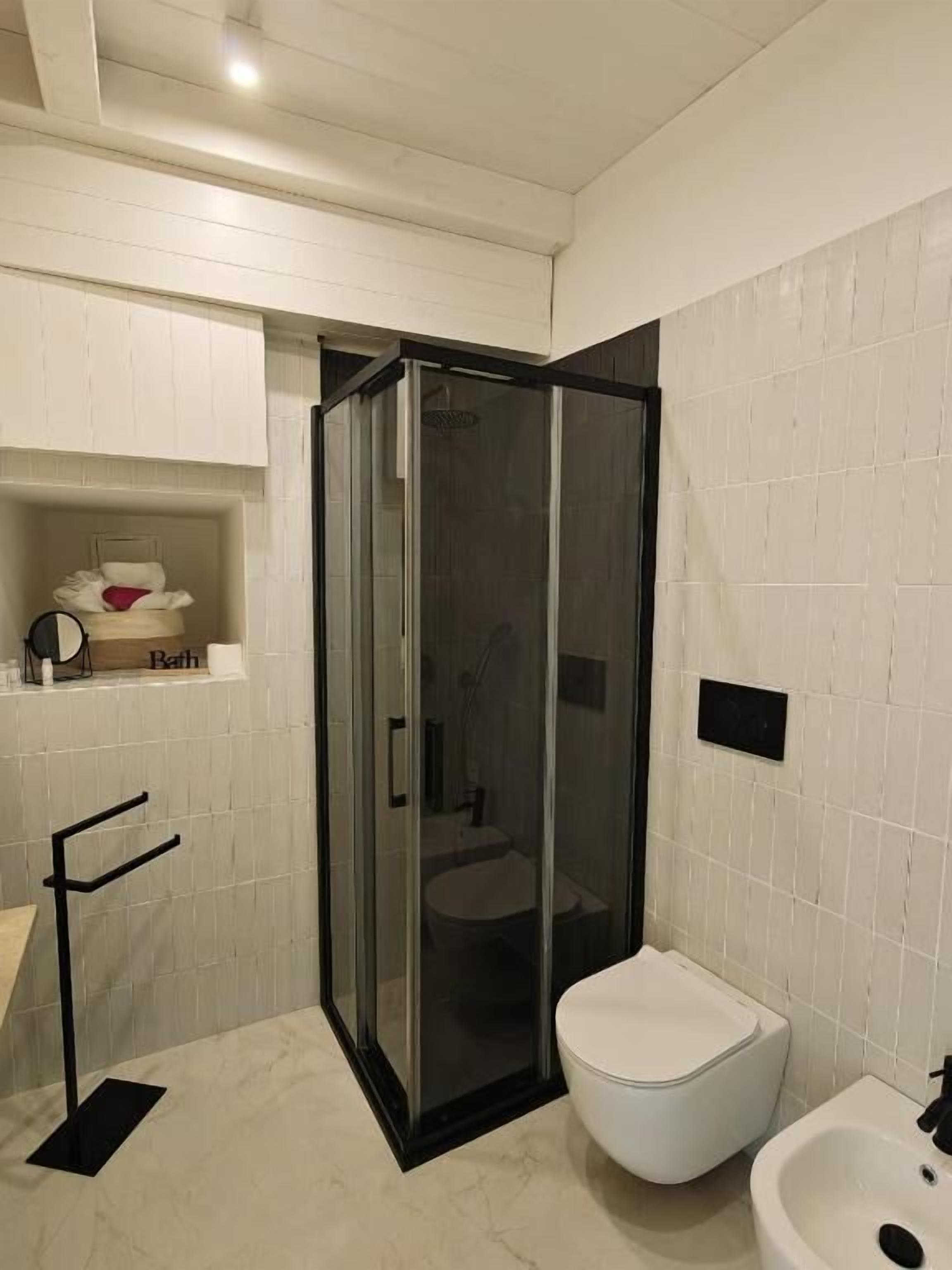 A bathroom with a glass-enclosed shower, a white toilet, and a sink.