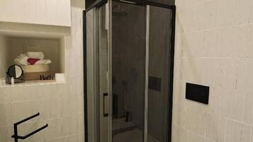 A bathroom with a glass-enclosed shower, a white toilet, and a sink.