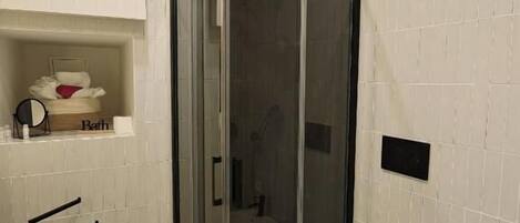 A bathroom with a glass-enclosed shower, a white toilet, and a sink.