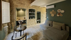 A rustic interior with stone walls, a dining area with a table and chairs, a sofa, and decorative wall art. - DOMUS GABRIEL (Giovinazzo)