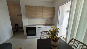 Ett modernt kök med träskåp, en diskho och en spis. Det finns en matplats med ett bord, stolar och en vas med blommor.