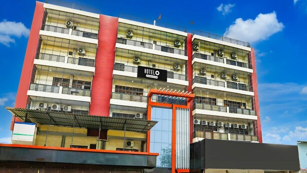 A multi-story hotel with balconies, a prominent red pillar, and a sign indicating it is a hotel. - Classic With Balcony Yug Residency (Varanasi)
