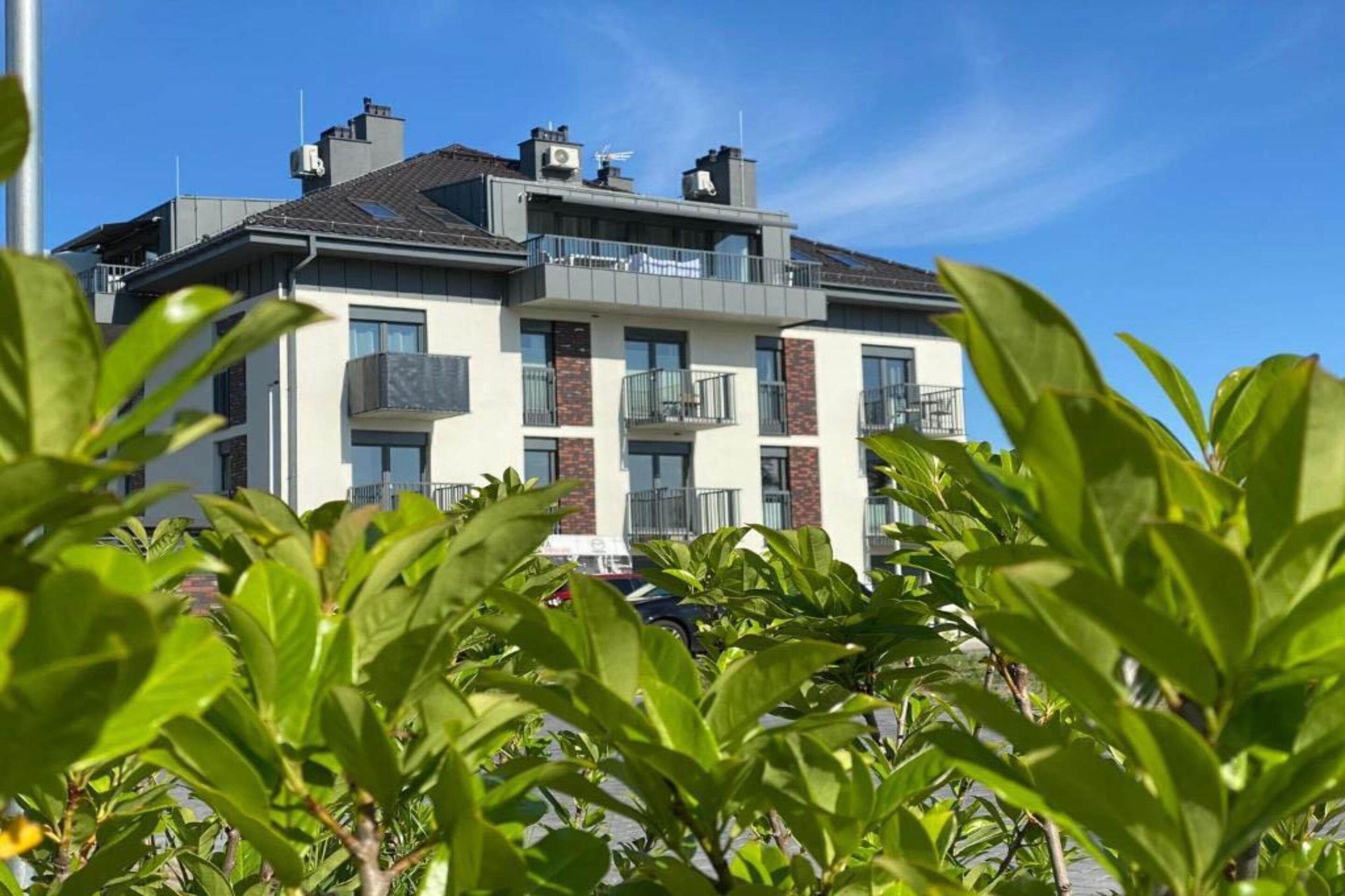 Ein mehrgeschossiges Wohngebäude mit Balkonen und blauem Himmel.