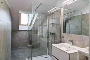 Une salle de bain moderne avec une douche à parois de verre, un grand miroir et un lavabo avec un meuble-vasque.